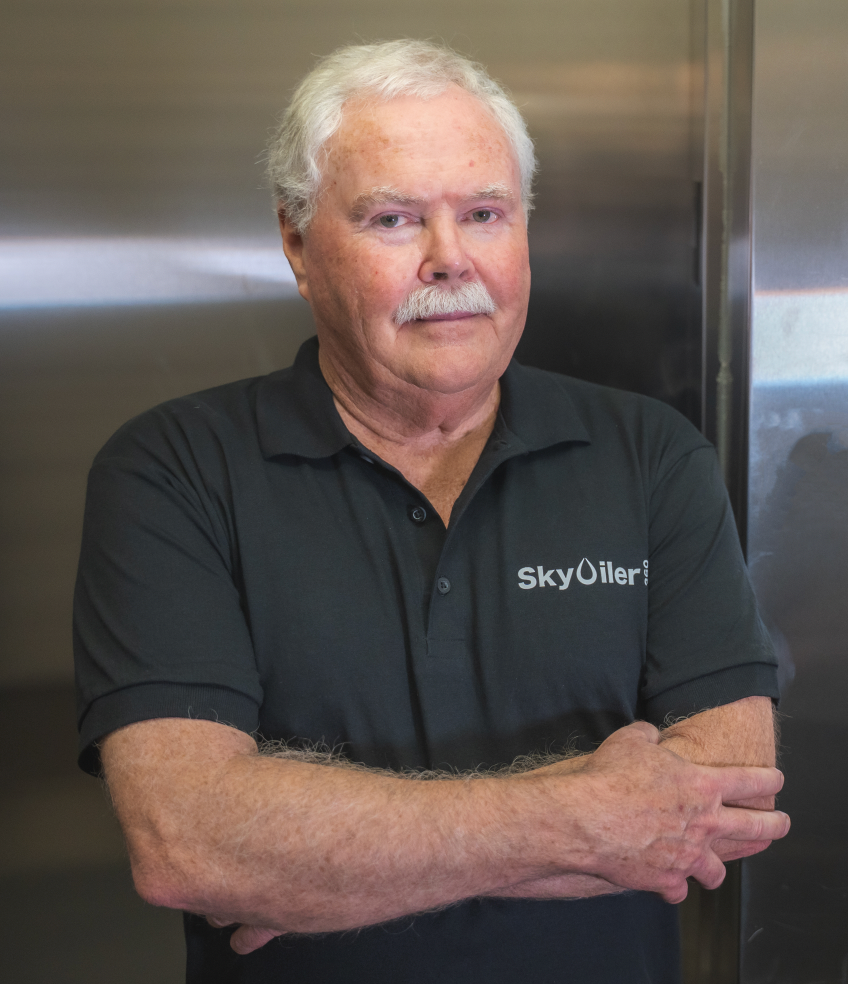 Man wearing a black polo shirt with 'SkyOil' logo against a metallic background